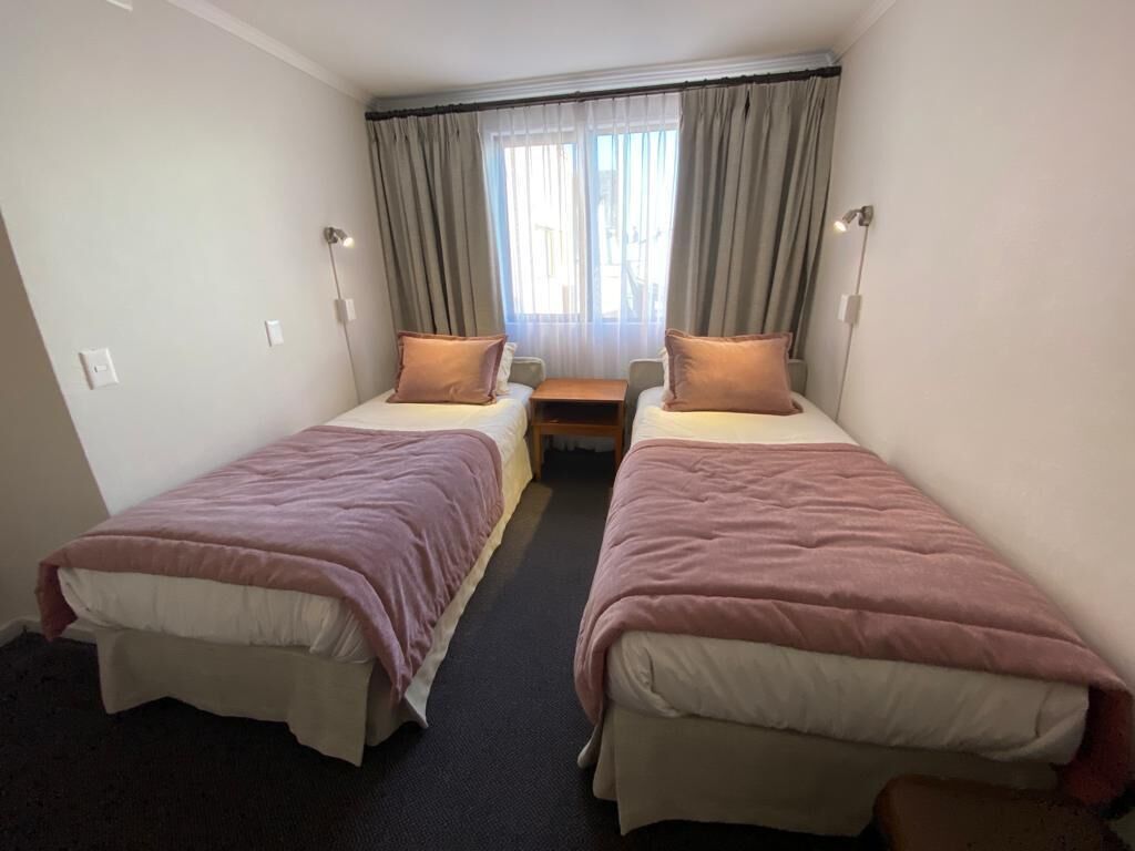 Una habitación con dos camas individuales, cada una con una almohada y una mesita de noche.
