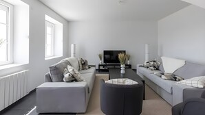 A modern living room with a grey sofa, a black ottoman, and a TV on a black stand. - Farmhouse in Laigne Near Le Mans Circuit (Laigné-en-Belin)