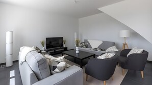 A modern living room with a flat-screen TV, grey sofas, a coffee table, and a floor lamp. - Farmhouse in Laigne Near Le Mans Circuit (Laigné-en-Belin)