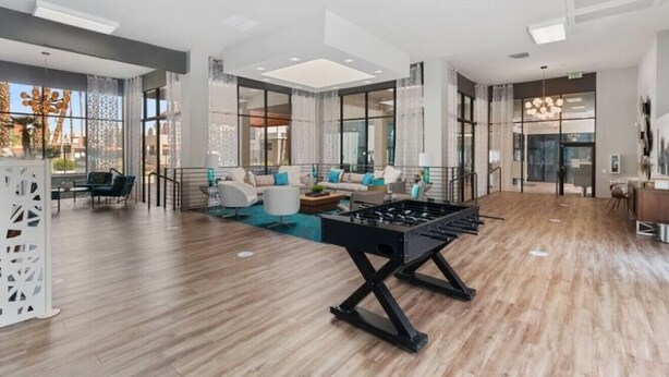 A spacious lobby with a foosball table, comfortable seating, and large windows offering views of the outdoors.