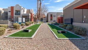 A courtyard with a gravel path, green lawns, and neatly trimmed bushes.