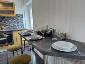 A modern kitchen with a dining area, featuring a Bosch oven, a checkered backsplash, and a minimalist design. - Duplex in Le Mans Near Place D'alger (Le Mans)