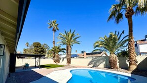 A swimming pool with a curved edge, surrounded by palm trees and a brick patio. - Charming 4-bedroom house with WiFi and AC in amazing Las Vegas (Las Vegas)