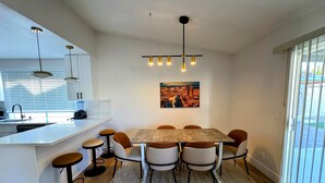 A modern kitchen with a central island, a dining area with a table and chairs, and a large window with blinds. - Charming 4-bedroom house with WiFi and AC in amazing Las Vegas (Las Vegas)