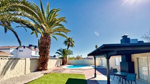 A backyard with a swimming pool, palm trees, a patio with chairs, and a brick pathway. - Charming 4-bedroom house with WiFi and AC in amazing Las Vegas (Las Vegas)
