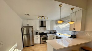 A modern kitchen with white cabinetry, stainless steel appliances, and a central island with stools. - Charming 4-bedroom house with WiFi and AC in amazing Las Vegas (Las Vegas)