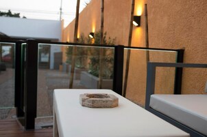 A modern outdoor seating area with a glass partition and a stone centerpiece on a white table.