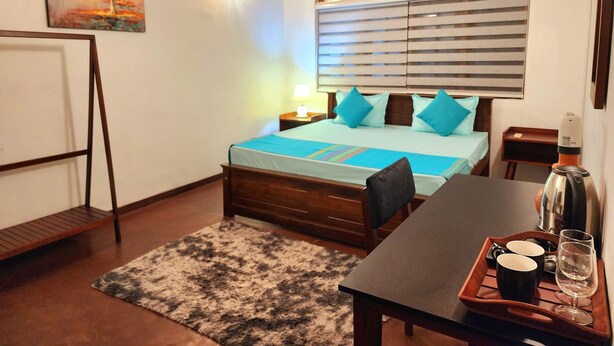 A neatly arranged bedroom with a bed, bedside tables, a desk with a chair, a rug, and a painting on the wall. - 2-bedroom house in marvelous Battaramulla with WiFi, AC (Battaramulla)