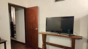 A room with a wooden TV stand, a closed door, and a hallway leading to another room. - 2-bedroom house in marvelous Battaramulla with WiFi, AC (Battaramulla)