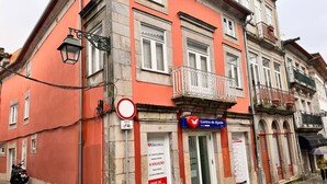 Un bâtiment à la façade rouge, une enseigne indiquant « Centro de Ajuda » et un panneau interdisant le stationnement.