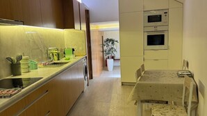 Une cuisine moderne avec des meubles en bois, une table à manger avec des chaises et des appareils électroménagers intégrés.