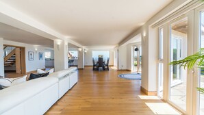 Ein großzügiger Wohnbereich mit Holzboden, einem weißen Sofa und einem Esstisch mit Stühlen.