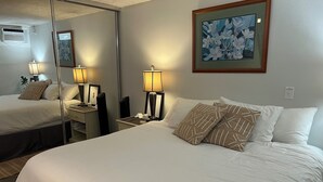 Une chambre d’hôtel avec un grand lit, deux lampes de chevet, un miroir et une œuvre d’art encadrée au mur.