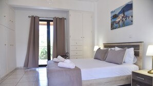 A hotel room with a bed, a nightstand, a lamp, a painting, and a view of the outdoors.
