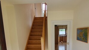 A wooden staircase leading to a kitchen with a tiled floor.