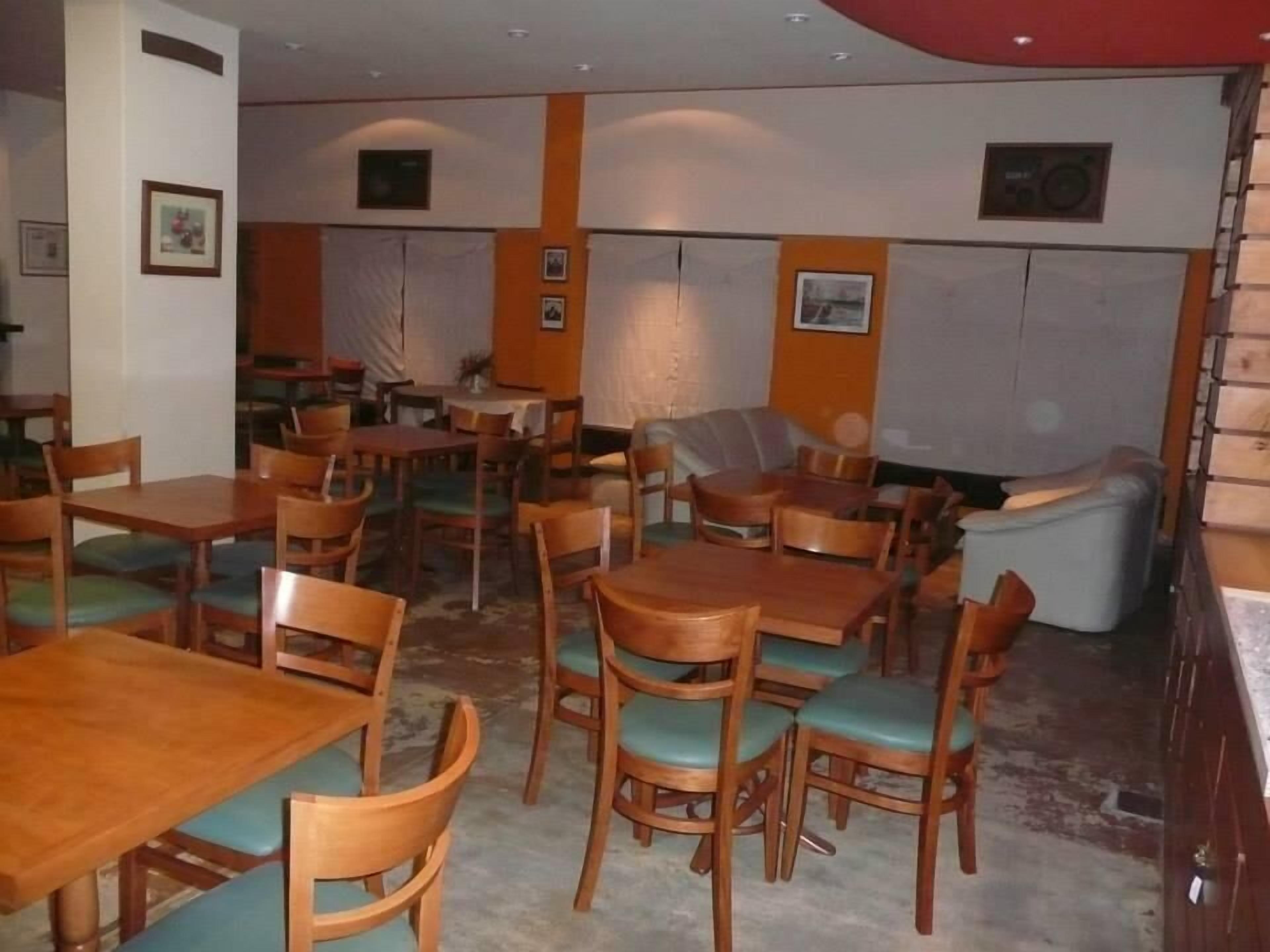 Un espace repas avec des tables et des chaises en bois, un canapé et un auvent rouge.