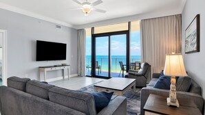 A modern living room with a flat-screen TV, grey sofas, a coffee table, and a lamp.