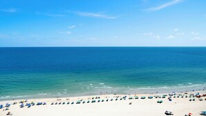 A beach with numerous umbrellas and people.