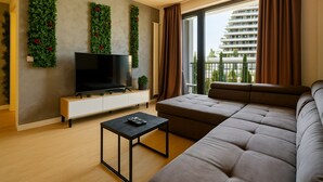 A modern living room with a large sectional sofa, a flat-screen TV, and a small table.