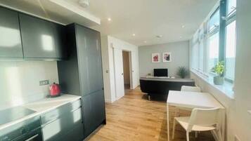A modern kitchen with dark cabinets, a white countertop, and a dining area with a white table and chairs.
