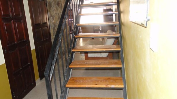 Un escalier en bois avec des rampes en métal menant à un palier.