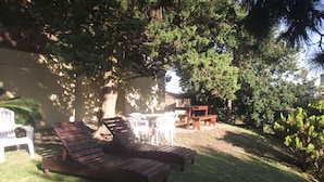 Ein Garten mit einer Holzbank, einem weißen Kunststoffstuhl und einem Tisch.