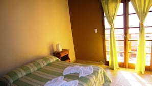 A hotel room with a bed, a nightstand, and a window with curtains.