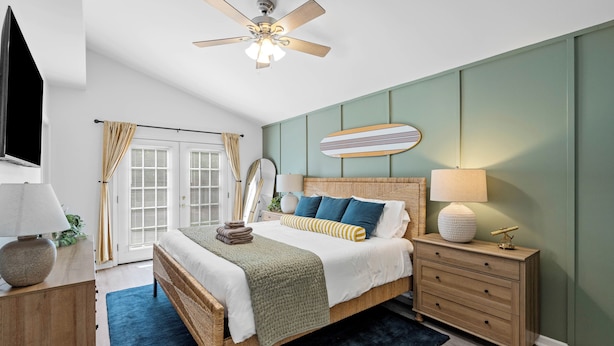 Une chambre à coucher avec un lit, une table de chevet, une lampe et un ventilateur de plafond.
