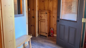 Eine Holztür mit Fenster, eine Bank und ein Feuerlöscher.