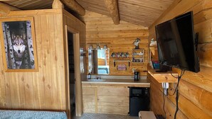 A wooden cabin interior with a bed, a kitchenette, a TV, and a bathroom. - Wolf Cabin-Modern Comfort in the Last Frontier (For families or casual travelers) (Tok)