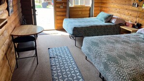 A cozy log cabin room with two beds, a small table, and a chair. - Wolf Cabin-Modern Comfort in the Last Frontier (For families or casual travelers) (Tok)