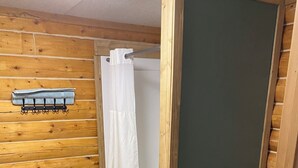 A wooden-paneled bathroom with a shower, a toilet, and a trash bin. - Fireweed Cabin-Modern Comfort in the Last Frontier (For families or casual travelers) (Tok)