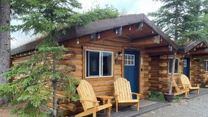 A log cabin with a porch, two Adirondack chairs, and a gravel driveway. - Fireweed Cabin-Modern Comfort in the Last Frontier (For families or casual travelers) (Tok)