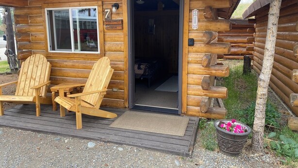 A log cabin with a wooden exterior, a door labeled "Firewood", and two Adirondack chairs outside. - Fireweed Cabin-Modern Comfort in the Last Frontier (For families or casual travelers) (Tok)
