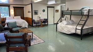 Une chambre de dortoir avec des lits superposés, un bureau, des chaises et une petite table.