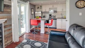 Una cucina moderna con mobili bianchi, un'isola centrale e sgabelli rossi.