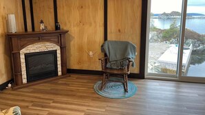 Un cuarto acogedor con chimenea, una mecedora y un amplio ventanal con vistas panorámicas.