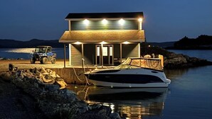 Una propiedad frente al agua con un barco amarrado, un edificio con porche y un cielo nocturno despejado.
