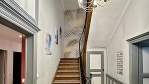 A staircase with a patterned carpet, a chandelier, and a wall with a decorative design. - Villa in Le Mans Near Plantagenet City (Le Mans)
