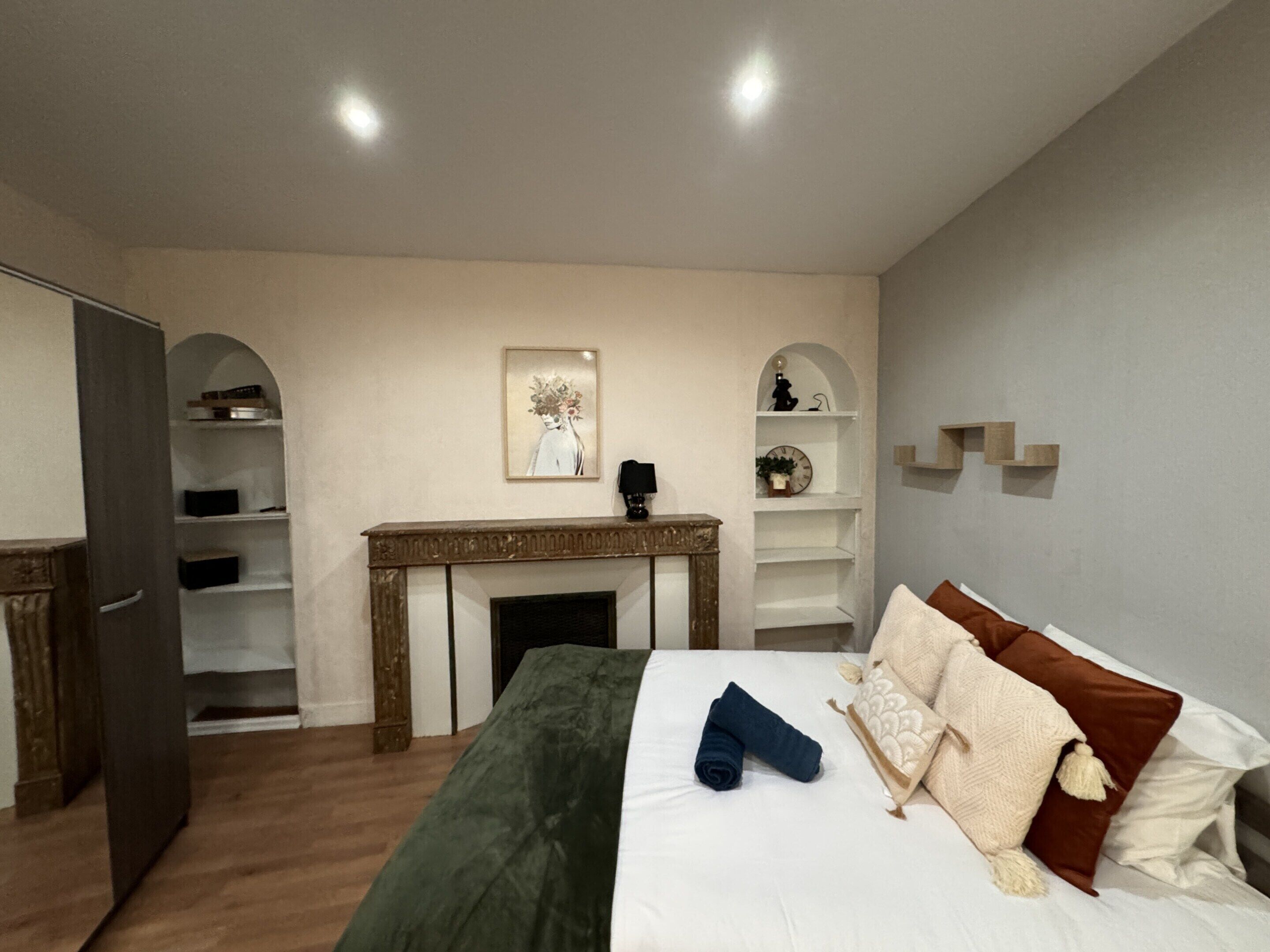 A bedroom with a bed, a fireplace, shelves, and a door.