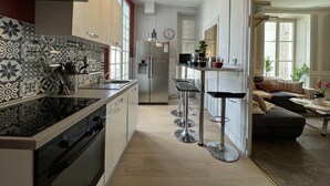 A modern kitchen with a central island, stainless steel appliances, and patterned backsplash tiles. - Villa in Le Mans Near Plantagenet City (Le Mans)