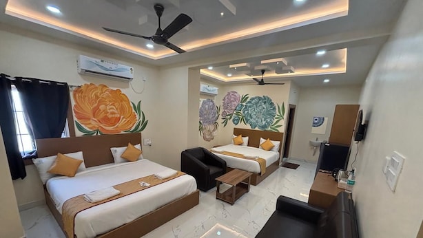 Habitación de hotel con dos camas, un sofá, un televisor y un ventilador de techo.