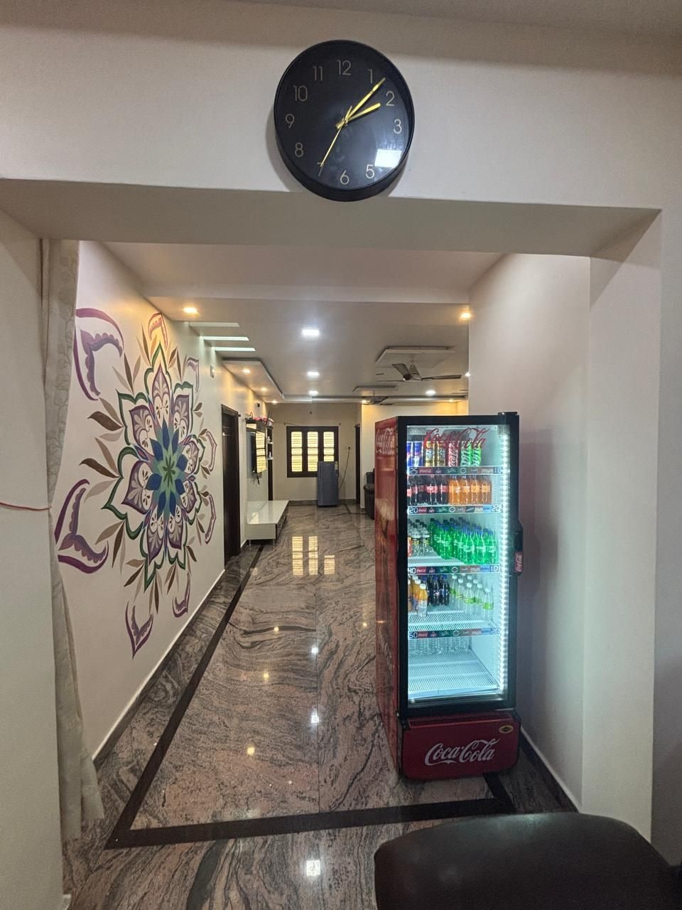 Un pasillo con un reloj, una máquina expendedora y un adornado mural.