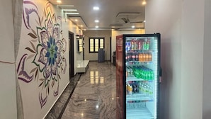 Un pasillo con un reloj, una máquina expendedora y un adornado mural.