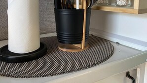En køkkenbordplade med papirhåndklædeholder, en utensilholder og en lille hylde med planter.