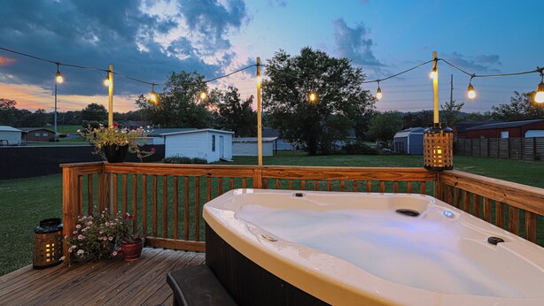 Ein Whirlpool auf einer Holzterrasse mit Lichterketten und Topfpflanzen.