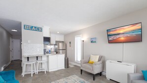 Una cocina moderna con armarios blancos, un refrigerador de acero inoxidable y una isla blanca con taburetes.