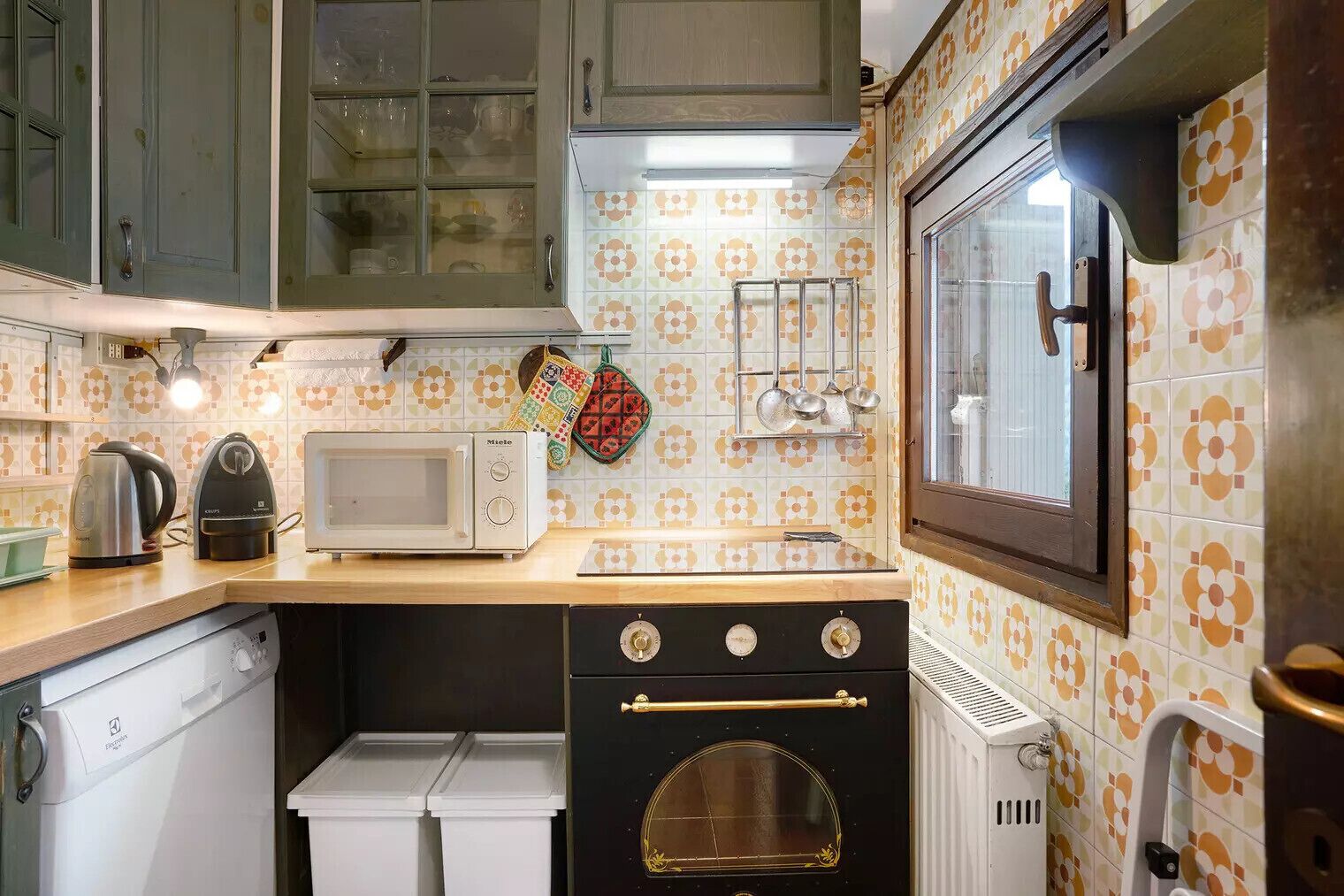 Una cocina equipada con microondas, hervidor, horno y diferentes utensilios.
