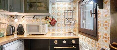 Una cocina equipada con microondas, hervidor, horno y diferentes utensilios.