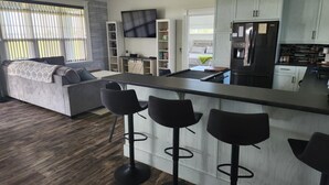 A modern kitchen with a bar area, built-in seating, and a large clock on the wall. - Cozy Waterfront Country Home w/game room. Close to all amenities! (Lot 19)